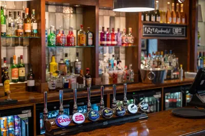 a bar with a bunch of bottles of alcohol at The Titan By Greene King Inns in Clydebank