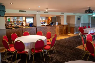 a conference room with tables and chairs and a bar at The Titan By Greene King Inns in Clydebank