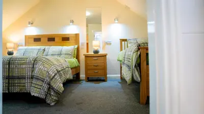a bedroom with two beds and a mirror at Braidmead House in Irvine