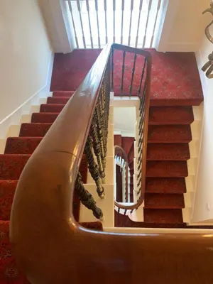 a stairway with a wooden railing and stairs with red carpet at Braidmead House in Irvine