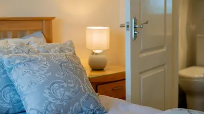 a bedroom with a bed with a blue comforter and a lamp at Braidmead House in Irvine