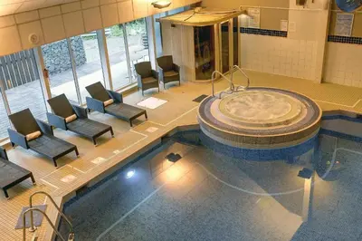 a swimming pool with chairs and a tub in a building at Buchanan Arms Hotel & Leisure, Sure Hotel Collection in Drymen