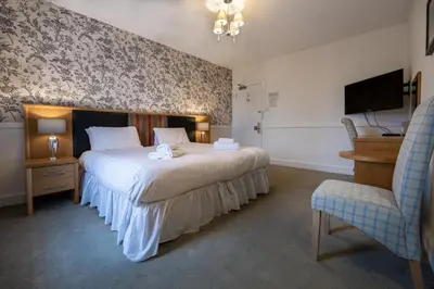 a bedroom with a bed and a chair and a television at Buchanan Arms Hotel & Leisure, Sure Hotel Collection in Drymen