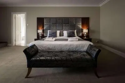 a bedroom with a large bed with a black leather couch at Buchanan Arms Hotel & Leisure, Sure Hotel Collection in Drymen