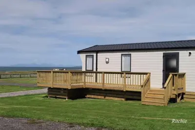 a mobile home with a large deck on the grass at Bellochantuy Beach in Bellochantuy
