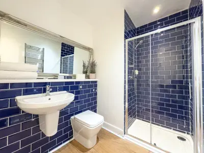a blue tiled bathroom with a toilet and a shower at Hanover 71 Suites in Edinburgh
