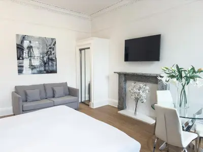 a white living room with a couch and a fireplace at Hanover 71 Suites in Edinburgh