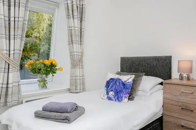 a bedroom with a bed and a window with a vase of flowers at 6 Beech Court in Dunblane