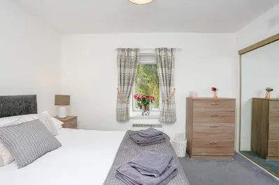 a white bedroom with a bed and a window at 6 Beech Court in Dunblane