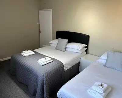 two beds with towels on top of them in a room at Nithsdale Hotel in Sanquhar