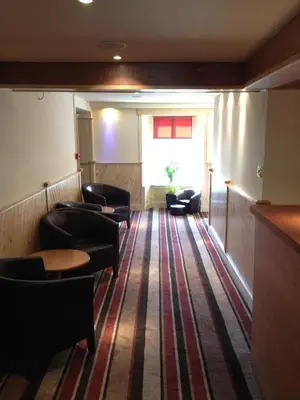 a waiting room with leather chairs and a window at Nithsdale Hotel in Sanquhar