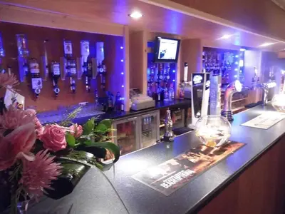 a bar with blue lights and a counter with flowers at Nithsdale Hotel in Sanquhar