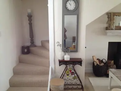 a staircase with a mirror and a clock on the wall at Sea Hollies in Aberdour