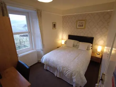 a bedroom with a bed with two pillows and a window at Inverardran House in Crianlarich
