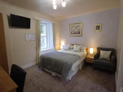 a bedroom with a bed and a window and a chair at Inverardran House in Crianlarich