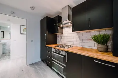 a kitchen with black cabinets and a counter top at SuperbSleep Apartments in Glasgow