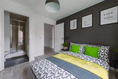 a bedroom with a large bed with green pillows at SuperbSleep Apartments in Glasgow