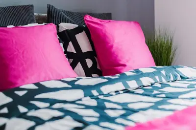 a bed with pink and blue pillows at SuperbSleep Apartments in Glasgow