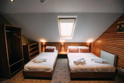 a attic bedroom with two beds and a window at The Commercial Hotel in Wishaw
