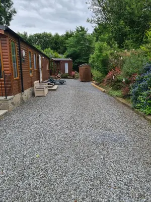 a gravel driveway with two benches next to a house at Bear Lodge in Auchterarder