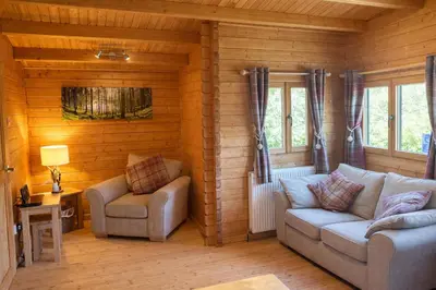 a living room with a couch and a chair at Lochinvar - Highland Log Cabin with Private Hot Tub in Airdrie