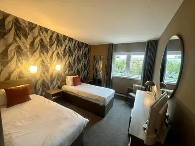 a hotel room with two beds and a chair at The Tontine Hotel in Greenock