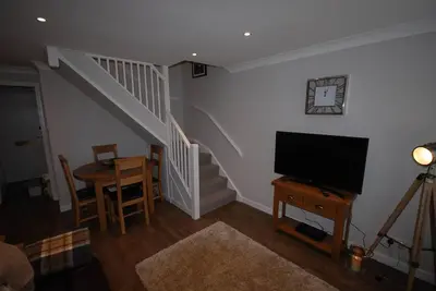 a living room with a staircase and a television at The Beeches at Gleneagles in Auchterarder
