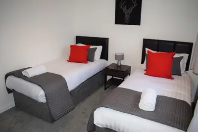two beds in a room with red and white pillows at Kelpies Serviced Apartments- Russell in Falkirk