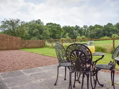 a table and chairs with a glass of orange juice on it at The Stables - Uk5532 in Kepculloch