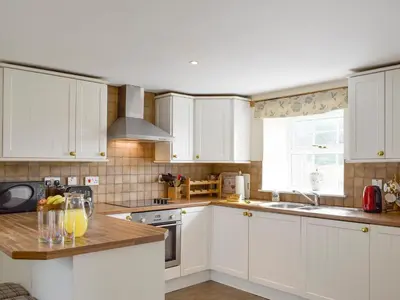 a kitchen with white cabinets and a counter with orange juice at The Stables - Uk5532 in Kepculloch