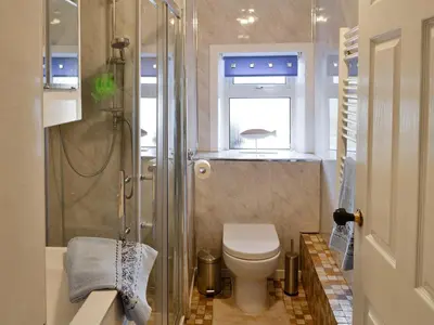 a bathroom with a toilet and a glass shower at Minnow Cottage in Newton Stewart