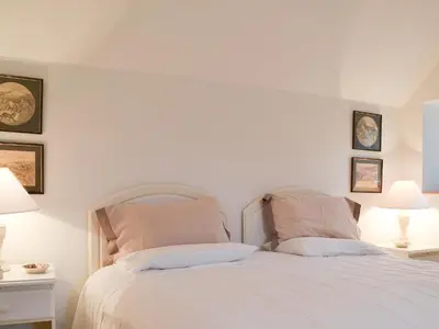 a bedroom with a white bed with two pillows at Garden Cottage in Strachur