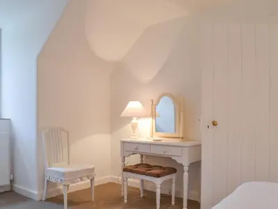 a bedroom with a table and a chair and a mirror at Garden Cottage in Strachur