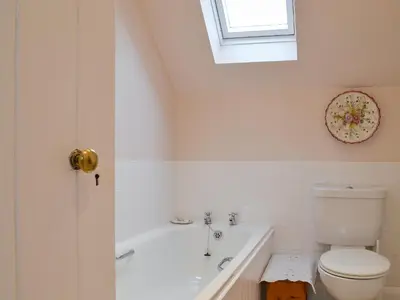 a bathroom with a tub and a toilet and a window at Garden Cottage in Strachur