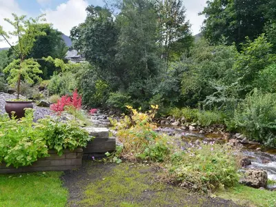 a garden with flowers and a stream at River Mill House in Ballachulish