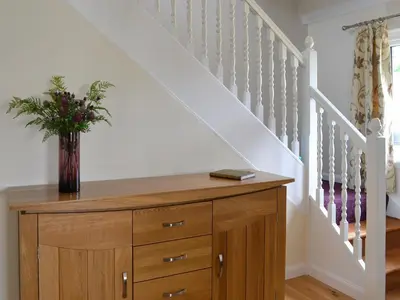 a wooden dresser with a vase of flowers on it at River Mill House in Ballachulish