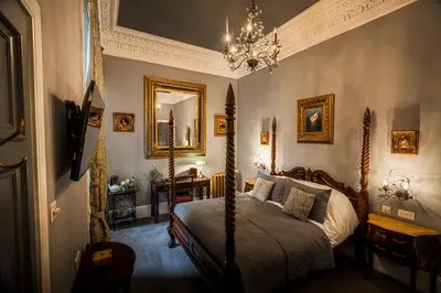 a bedroom with a bed and a chandelier at The Alamo Guest House in Glasgow