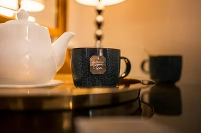 a coffee cup sitting on a table next to a teapot at The Alamo Guest House in Glasgow