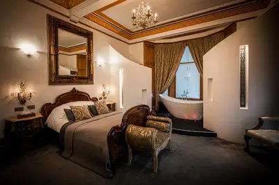 a bedroom with a bed and a tub and a mirror at The Alamo Guest House in Glasgow