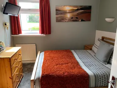 a bedroom with a bed with a dresser and a window at Greenacre in Oban