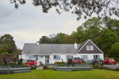 a white house with a lot of chairs in the yard at Greenacre in Oban