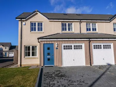 a house with two garage doors on a driveway at Holiday Home Devonvale Place by Interhome in Kinross