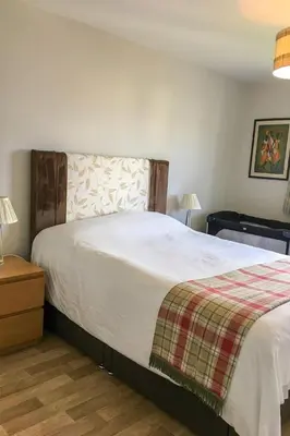 a bedroom with a large bed with a plaid blanket at Holiday Home Devonvale Place by Interhome in Kinross