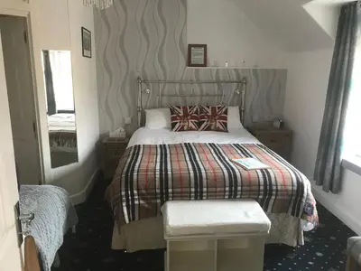 a bedroom with a bed with a blanket and a mirror at glenardran house in Crianlarich
