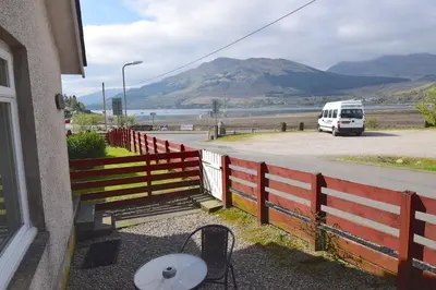 a bus driving down a road next to a fence at Feorline Cottage in Lochgoilhead