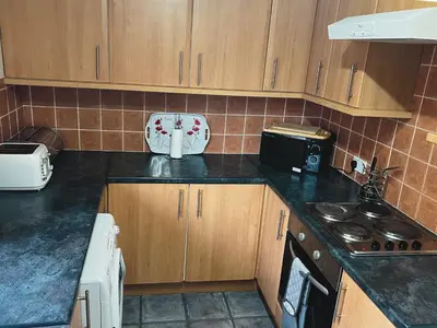 a kitchen with wooden cabinets and a black counter top at Feorline Cottage in Lochgoilhead