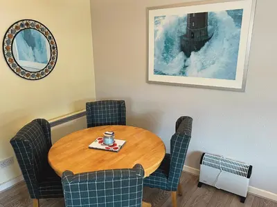 a room with a table and chairs with a coffeeucer on top at Feorline Cottage in Lochgoilhead