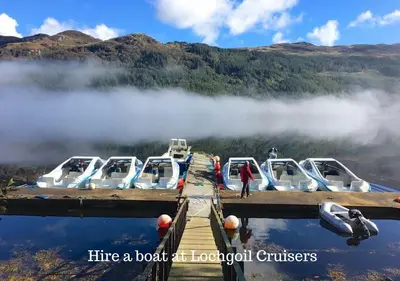 a group of boats parked at a dock on a lake at Armadale Cottage in Lochgoilhead