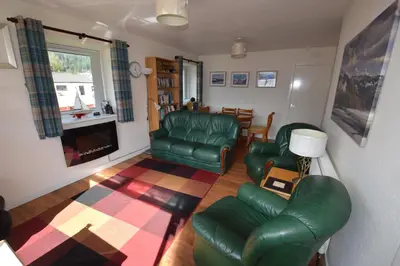 a living room with green leather furniture and a fireplace at Armadale Cottage in Lochgoilhead