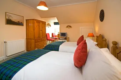 a bedroom with two beds with red pillows at Knap Guest House in Tarbert